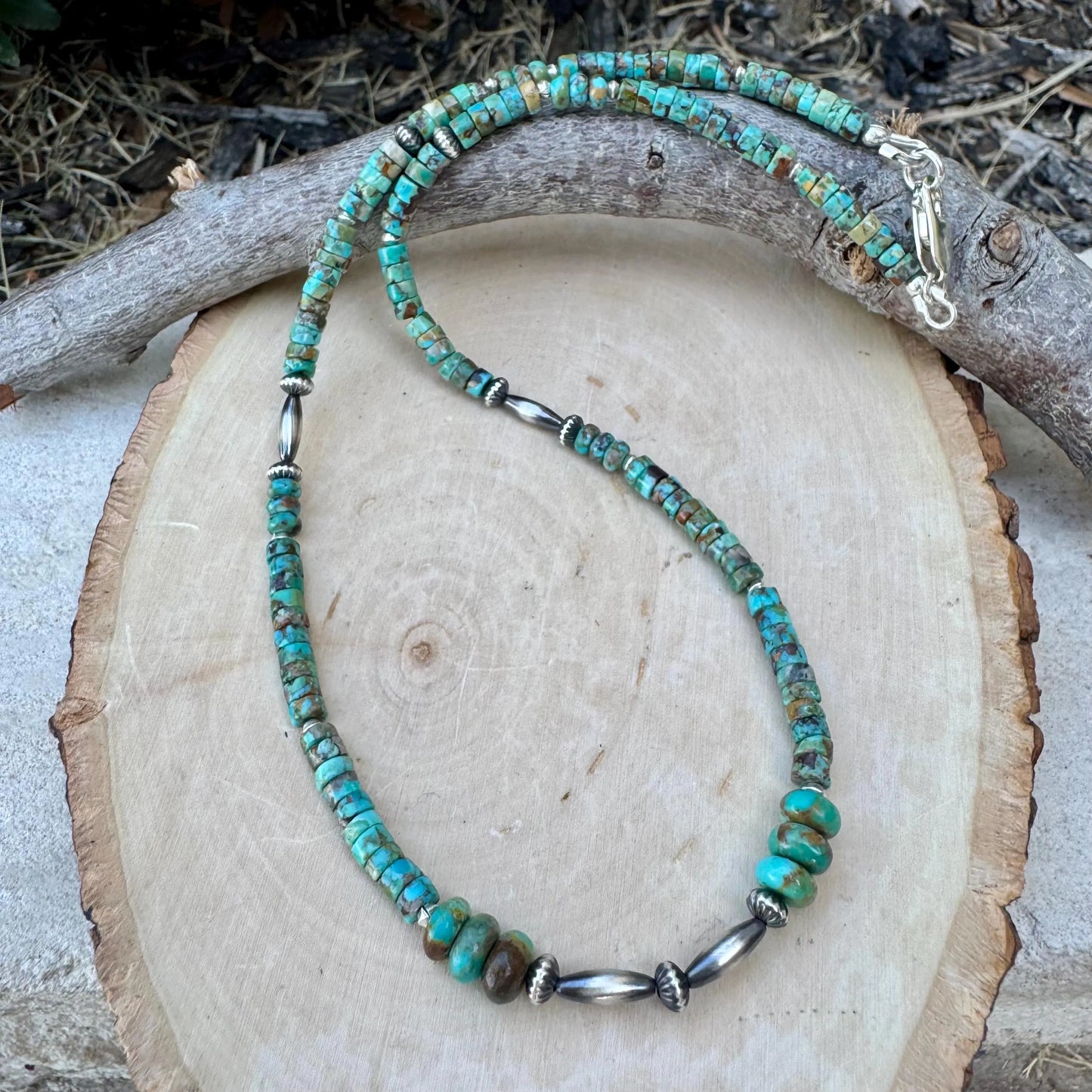 Turquoise beaded necklace with silver accents on a wooden surface